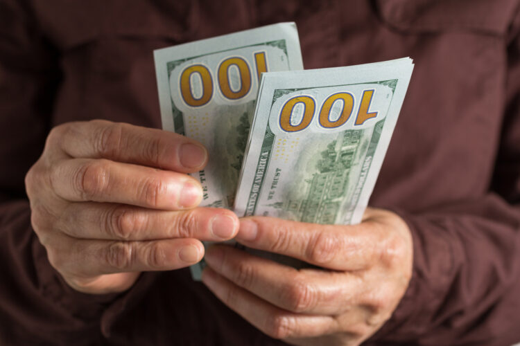 Cash bills from USA currency. Dollars. Front view of old woman's hand handling bills.