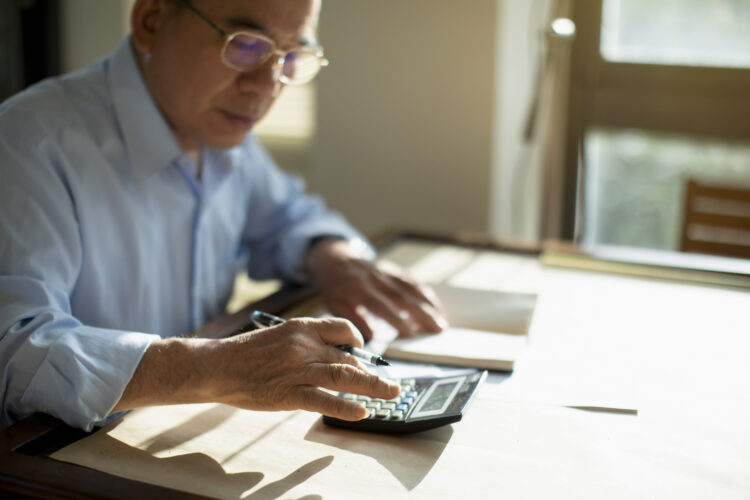 Taiwanese senior man sitting at table and calculating finances