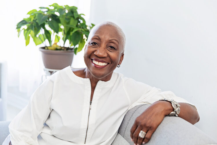 Cheerful senior woman sitting on the couch at home, relaxing. Well dressed and confident.