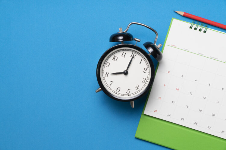 close up of calendar and alarm clock on the blue table background, planning for business meeting or travel planning concept