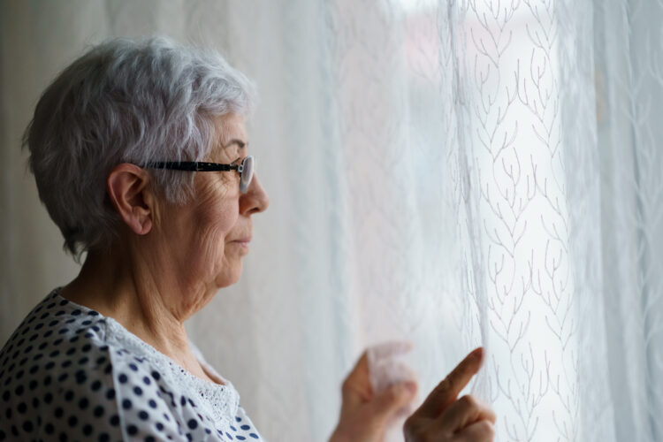 Senior White Haired Woman standing in front of a window