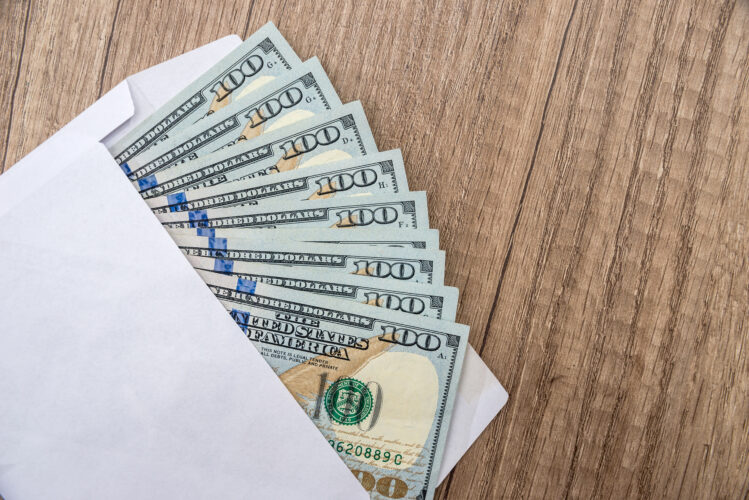 Dollars lie in envelope on wooden desk. concept of bribery or corruption.