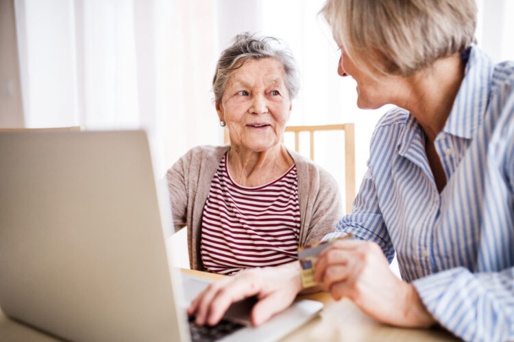 Unrecognizable senior woman with her mother with laptop at home. Family and generations concept.