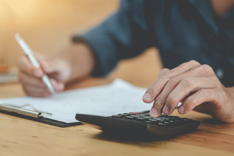 Man using calculator and writing make note with calculate about cost